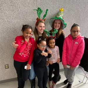 Emerging Leaders United members smiling with kids in holiday apparel