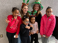 Emerging Leaders United volunteers smiling in holiday apparel with kids