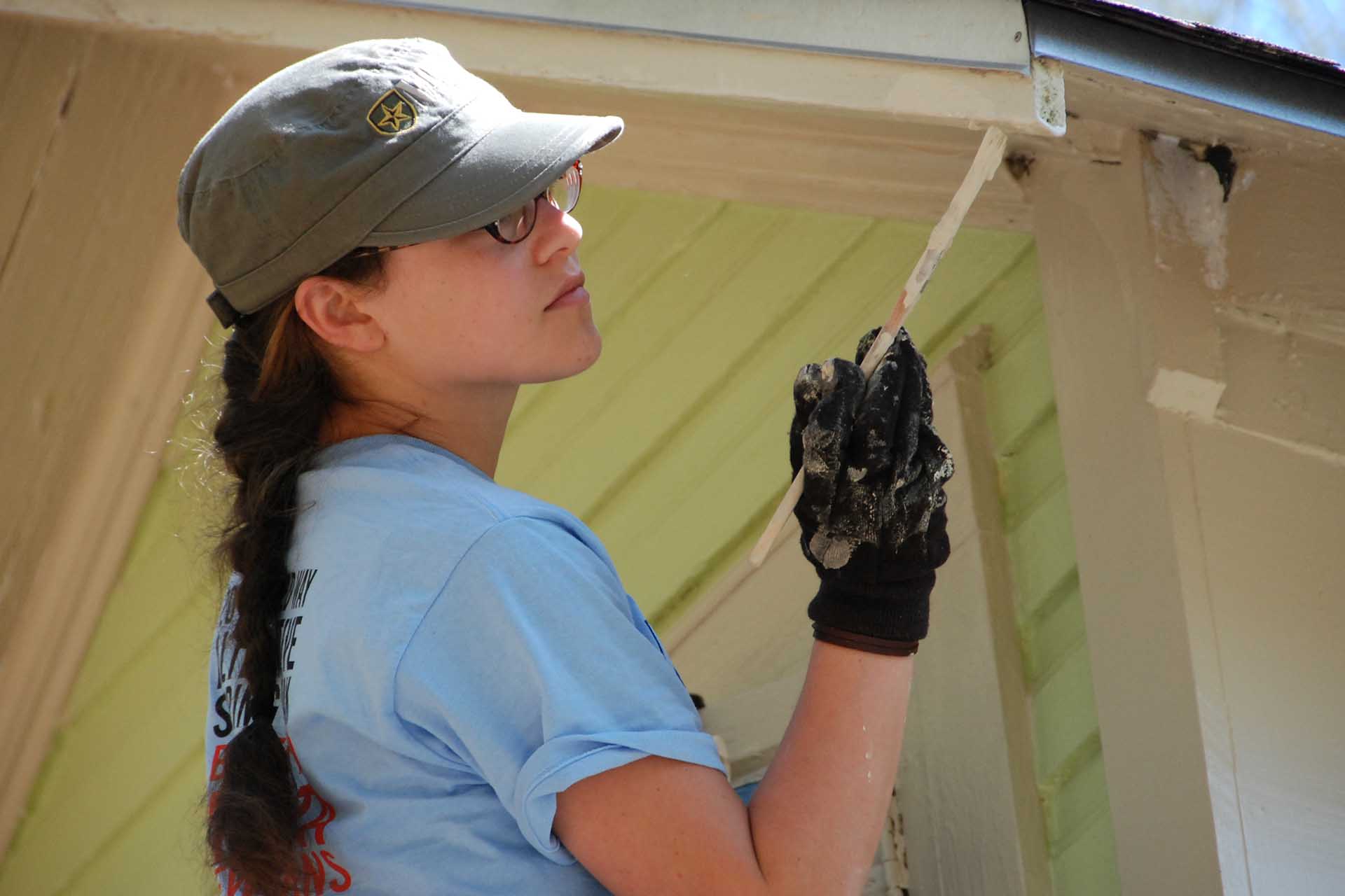 Teen girl painting trim on a house