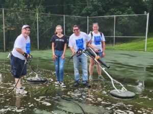 a group of volunteers are power washing a tennis court