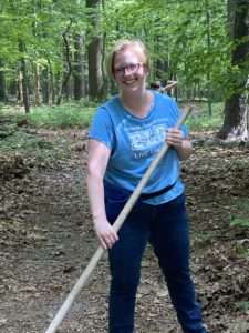 A woman in a blue shirt is raking trail at Nolde Forest