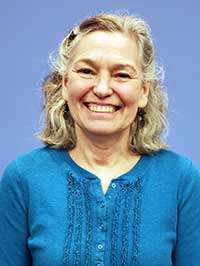 A woman in a blue shirt is smiling at the camera