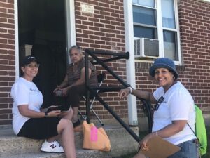 Three women are sitting on steps outside a home in the Oakbrook neighborhood
