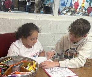 An elementary-school-aged girl is being tutored by a teenage boy