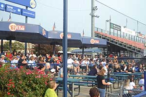A large group of people are sitting in the picnic area at FirstEnergy Stadium on a sunny morning