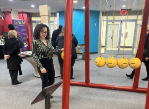 A woman tests a large Newton's Cradle at the Reading Science Center