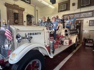 Volunteers looking at the camera on board a vintage fire engine