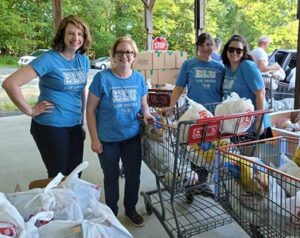 4 female volunteers smiling at the camera with two shopping carts full of food