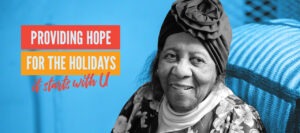 An older woman wearing a turban is sitting her bedroom. She smiles off to the side. The words Providing Hope for the Holidays It Starts with U are to the left of her photo