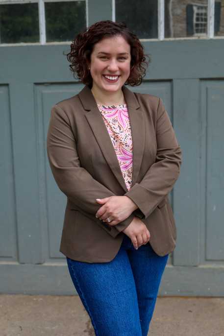 A woman is standing outside in front of a set of green garage doors with windows along the top