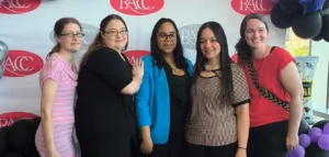 Five women are standing in front of a backdrop banner featuring the Reading Area Community College logo