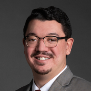 Head shot of a man standing against a gray background