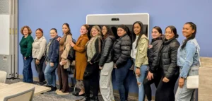 A group of women are standing together in a conference room and smiling