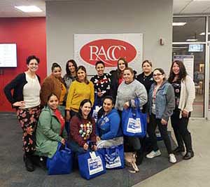A group of women are gathered in the lobby of Reading Area Community College. They are all smiling at the camera