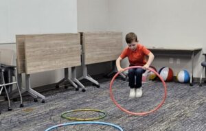 A boy is jumping through a hula hoop