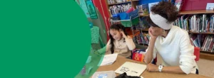 A woman is tutoring a student in a school library
