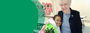 A woman is standing with one of the elementary-aged students she tutors