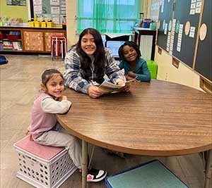 A teen girl is sitting in a classroom with two students