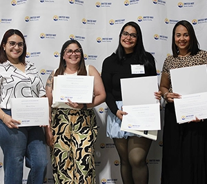 Four women are standing in front of the United Way of Berks County backdrop and holding certificates